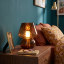 Seraphine glass mushroom lamp lit on a walnut bedside table