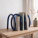Finch tabletop bookshelf in blue on a pale oak console with books between the coils
